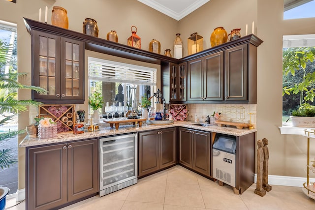 bar featuring light stone counters, dark brown cabinets, and beverage cooler