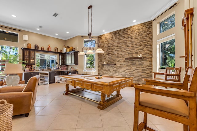 rec room with ornamental molding, beverage cooler, a wealth of natural light, and light tile patterned floors