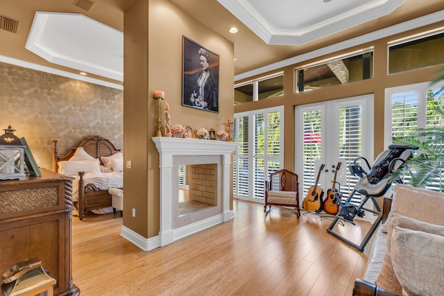 workout room featuring crown molding, a tray ceiling, french doors, and light wood-type flooring