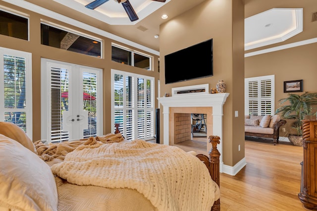 bedroom featuring ornamental molding, access to exterior, light hardwood / wood-style flooring, and a high ceiling