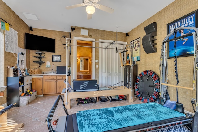 exercise area featuring ceiling fan, sink, and light tile patterned floors