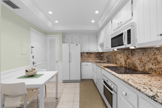 kitchen featuring sink, white cabinets, a tray ceiling, light stone countertops, and white appliances