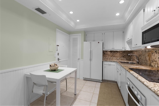 kitchen featuring sink, white cabinetry, stainless steel appliances, light stone countertops, and a raised ceiling