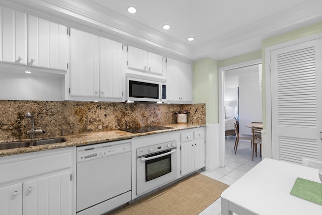 kitchen with sink, white cabinets, decorative backsplash, light tile patterned floors, and white appliances