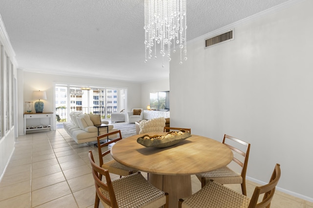 tiled dining room with an inviting chandelier, ornamental molding, and a textured ceiling