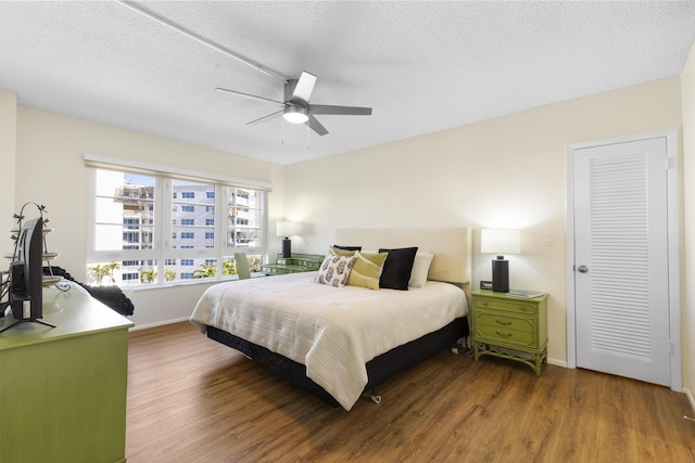 bedroom featuring ceiling fan, baseboards, wood finished floors, and a textured ceiling