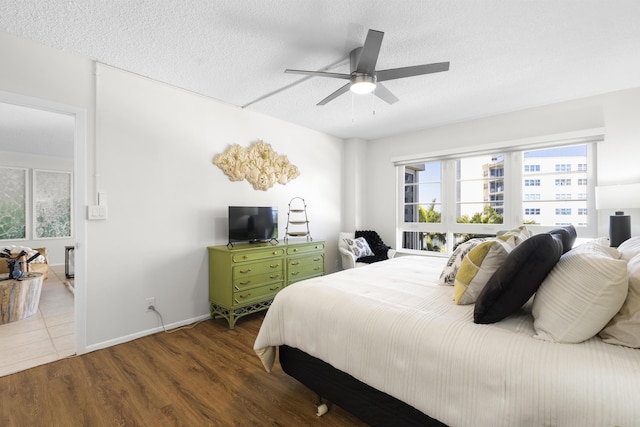 bedroom with baseboards, a ceiling fan, wood finished floors, and a textured ceiling