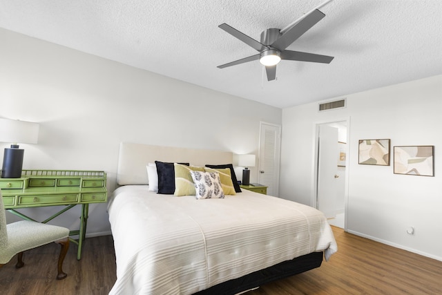 bedroom with ceiling fan, dark hardwood / wood-style flooring, and a textured ceiling