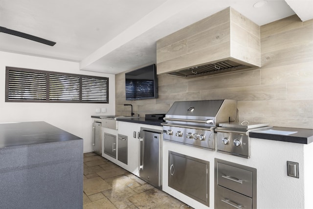 kitchen featuring stone tile flooring, dark countertops, fridge, and a sink