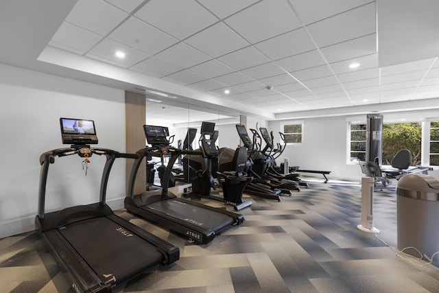 exercise room with baseboards, carpet floors, a drop ceiling, and a healthy amount of sunlight