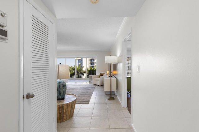 hall with ornamental molding and light tile patterned floors