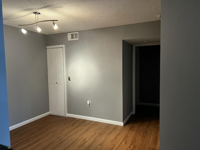 empty room featuring wood-type flooring and a textured ceiling