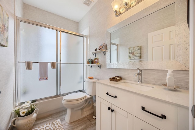 full bathroom with vanity, enclosed tub / shower combo, and toilet