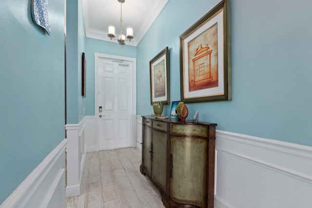 doorway to outside featuring a notable chandelier, light hardwood / wood-style flooring, and ornamental molding