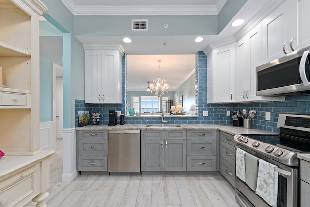 kitchen featuring appliances with stainless steel finishes, decorative light fixtures, white cabinetry, gray cabinetry, and crown molding