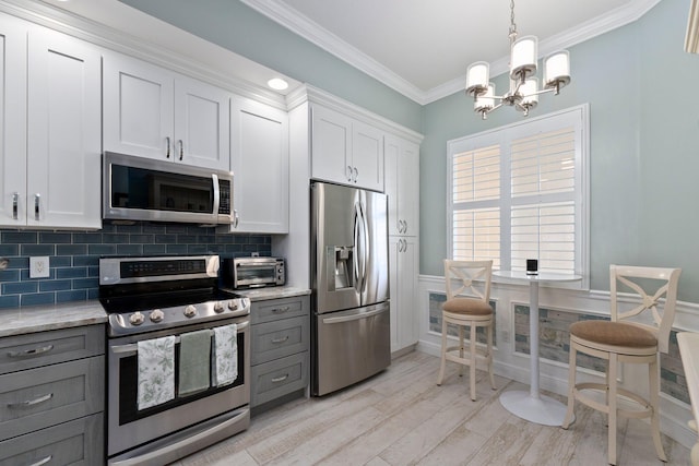 kitchen featuring gray cabinetry, light stone counters, white cabinets, and appliances with stainless steel finishes