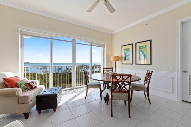 tiled dining space featuring crown molding, ceiling fan, and a water view