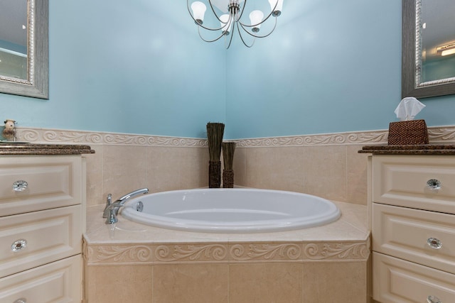 bathroom with vanity, tiled tub, and a notable chandelier