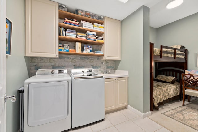 washroom featuring sink, light tile patterned floors, cabinets, and washing machine and clothes dryer