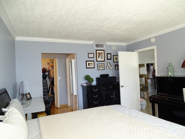 bedroom featuring ornamental molding, wood-type flooring, a textured ceiling, and a spacious closet