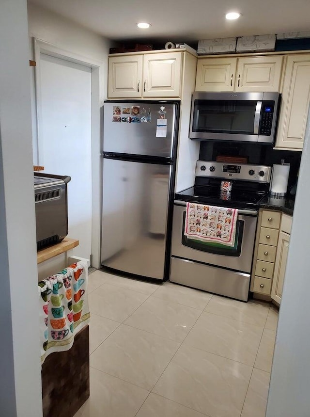 kitchen with cream cabinets, light tile patterned flooring, and appliances with stainless steel finishes