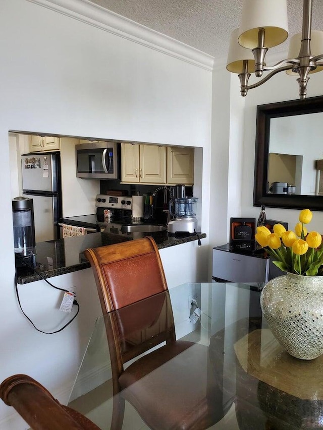 kitchen featuring stainless steel appliances, ornamental molding, cream cabinets, and a textured ceiling