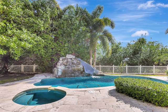 view of swimming pool featuring an in ground hot tub and a water slide