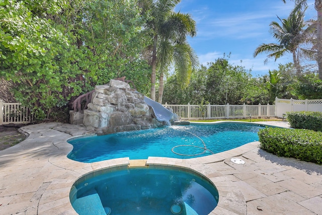 view of pool featuring an in ground hot tub, a water slide, and a patio area