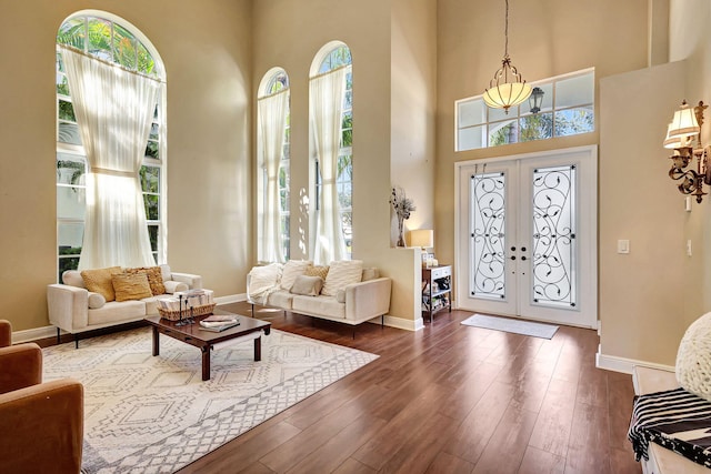 entrance foyer featuring a towering ceiling, dark wood-type flooring, and french doors