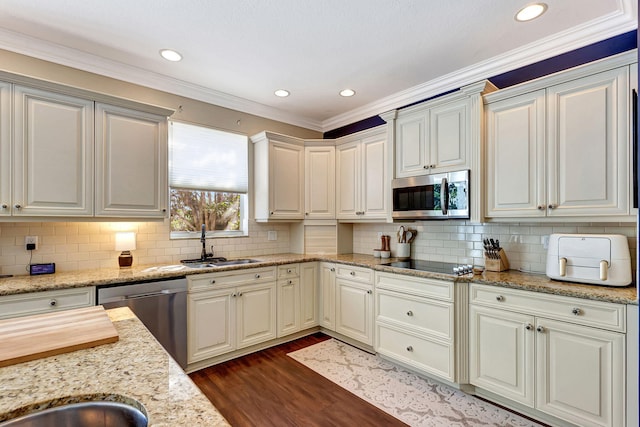 kitchen with sink, light stone counters, crown molding, appliances with stainless steel finishes, and dark hardwood / wood-style flooring