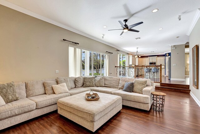 living room with crown molding, dark wood-type flooring, and ceiling fan