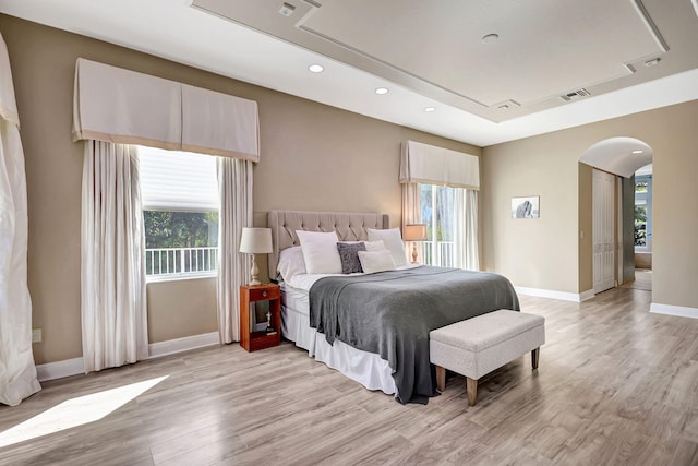 bedroom featuring light wood-type flooring and a tray ceiling