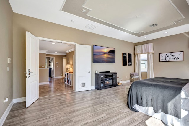 bedroom featuring light hardwood / wood-style floors and a raised ceiling