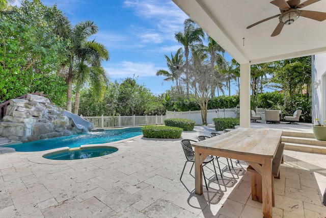 view of pool featuring an in ground hot tub, pool water feature, a water slide, ceiling fan, and a patio area