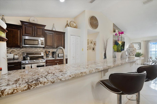 kitchen featuring stainless steel appliances, tasteful backsplash, lofted ceiling, and a breakfast bar area