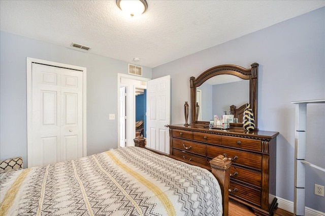 bedroom with fridge, a closet, and a textured ceiling