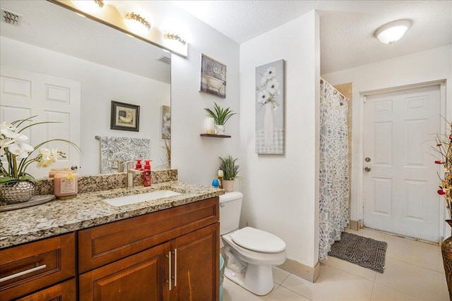 bathroom featuring vanity, a textured ceiling, tile patterned floors, and toilet