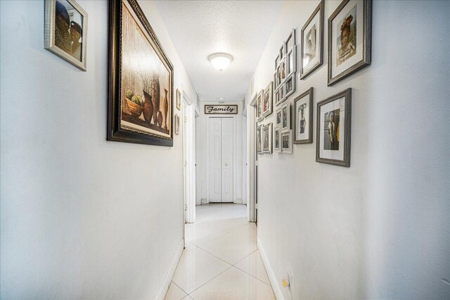 hall featuring light tile patterned floors and a textured ceiling