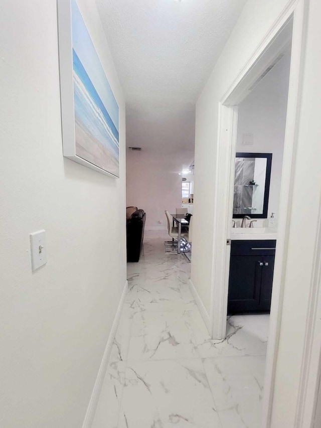 hall featuring sink and a textured ceiling