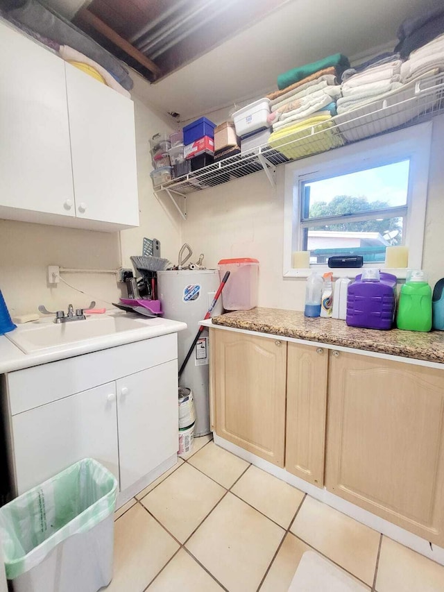 clothes washing area featuring sink, water heater, and light tile patterned floors