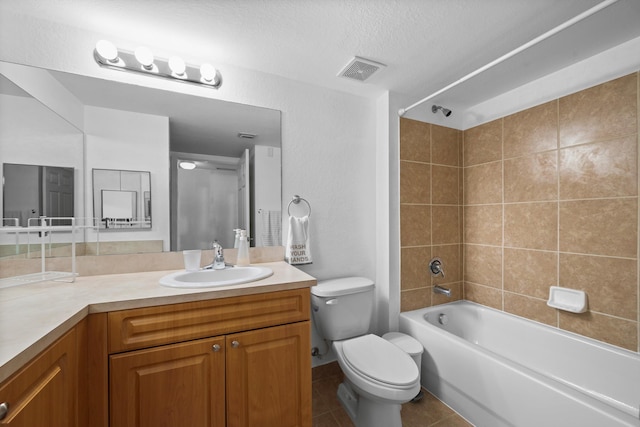 full bathroom with tiled shower / bath combo, vanity, a textured ceiling, tile patterned floors, and toilet