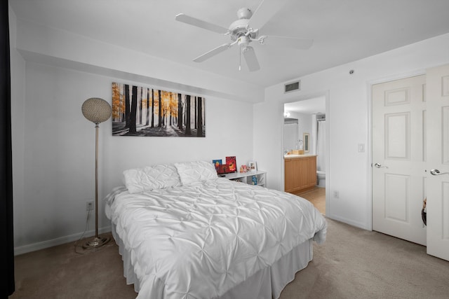 bedroom with ceiling fan, ensuite bathroom, and light carpet