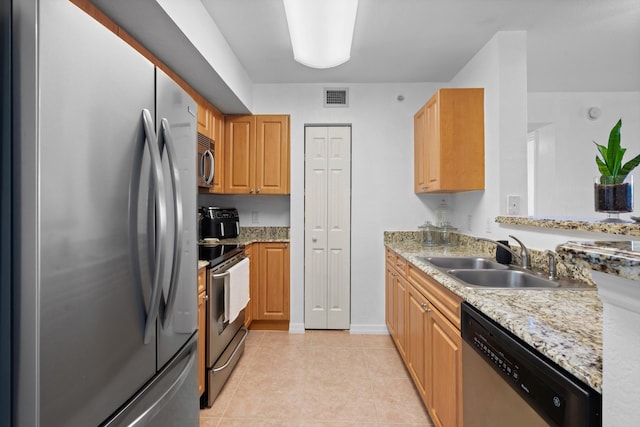 kitchen featuring light stone counters, sink, light tile patterned floors, and stainless steel appliances