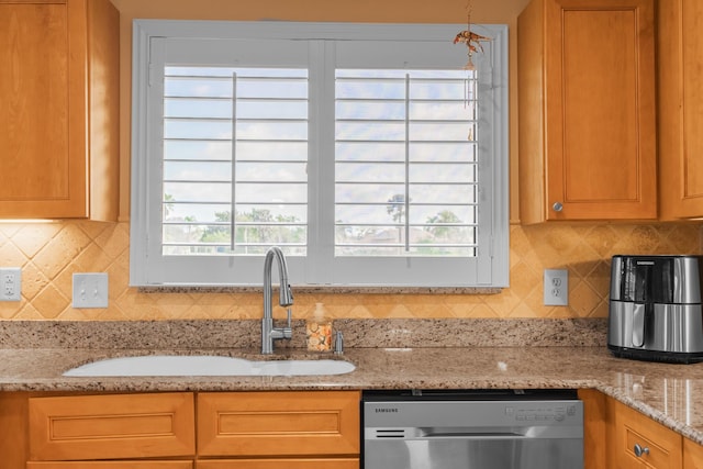 kitchen with sink, plenty of natural light, stainless steel dishwasher, and light stone countertops