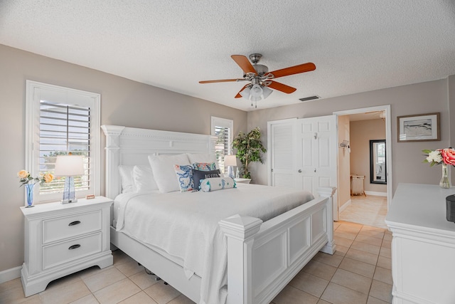 bedroom with visible vents, a textured ceiling, a closet, and light tile patterned flooring