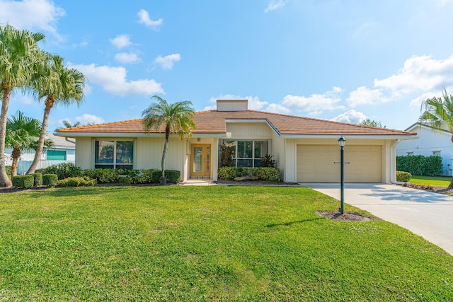 view of front of house with a tile roof, concrete driveway, a garage, and a front yard