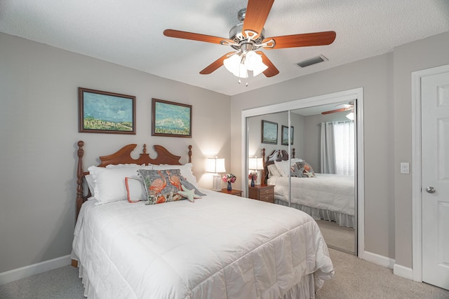 carpeted bedroom featuring ceiling fan, a closet, and a textured ceiling