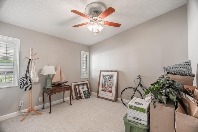 misc room featuring a textured ceiling, baseboards, carpet, and ceiling fan