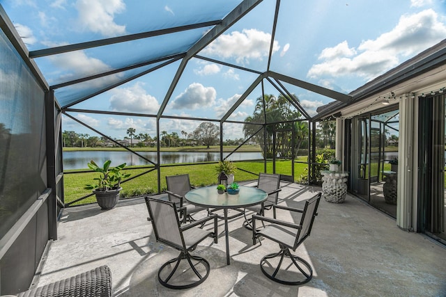 view of patio / terrace with a lanai, outdoor dining area, and a water view