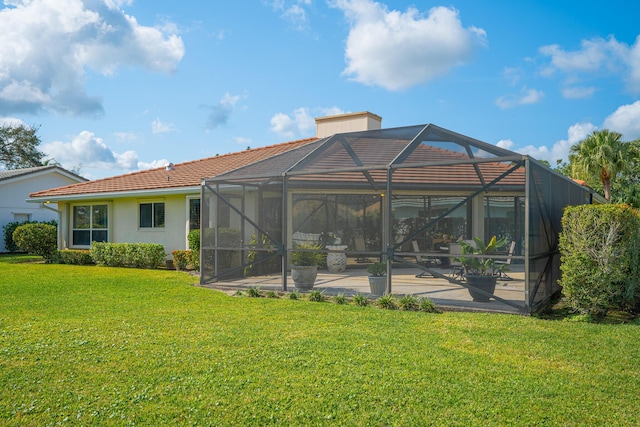 back of property featuring glass enclosure, a pool, stucco siding, a patio area, and a lawn